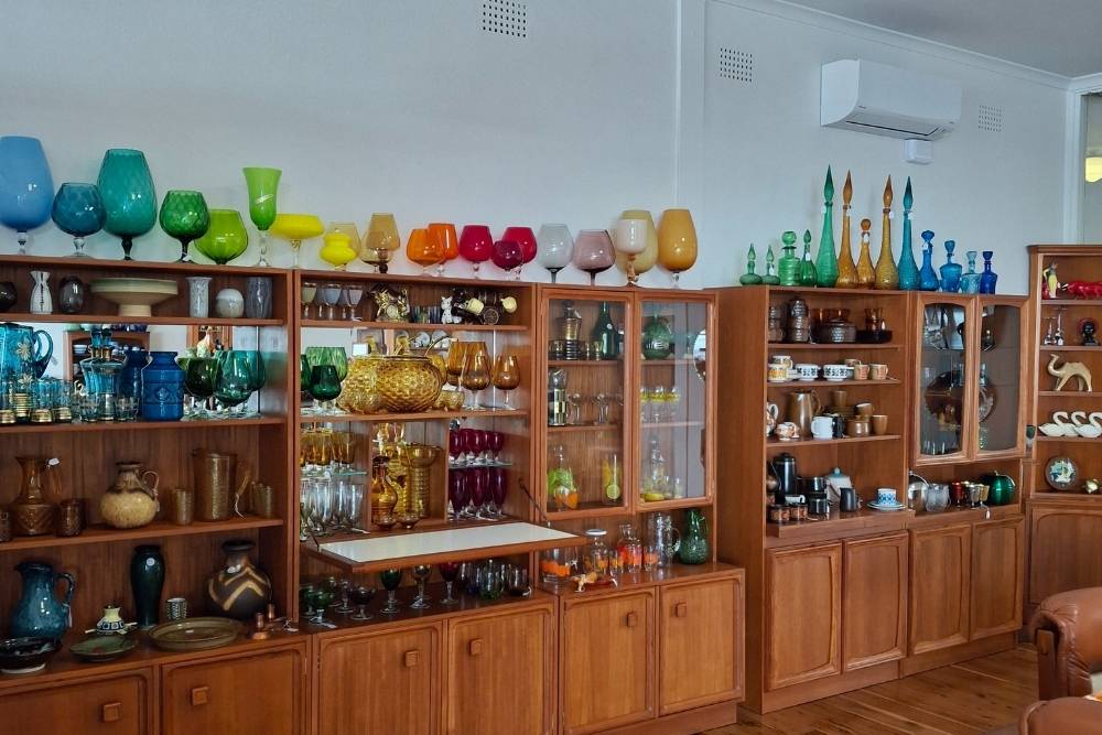 Display of colorful vintage glassware and mid-century wooden cabinets-